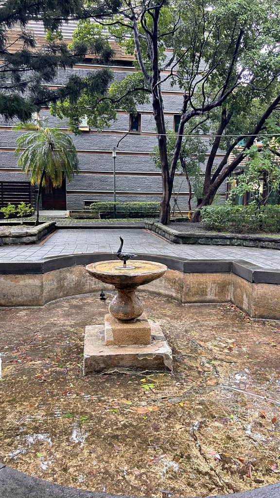A stone fountain sits in the center of a courtyard, surrounded by a circular stone ledge