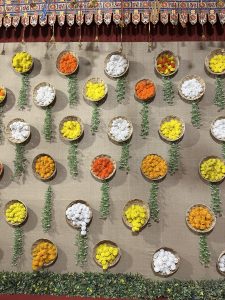 A decorative wall with circular baskets filled with vibrant artificial flowers in yellow, orange, white, and red.
