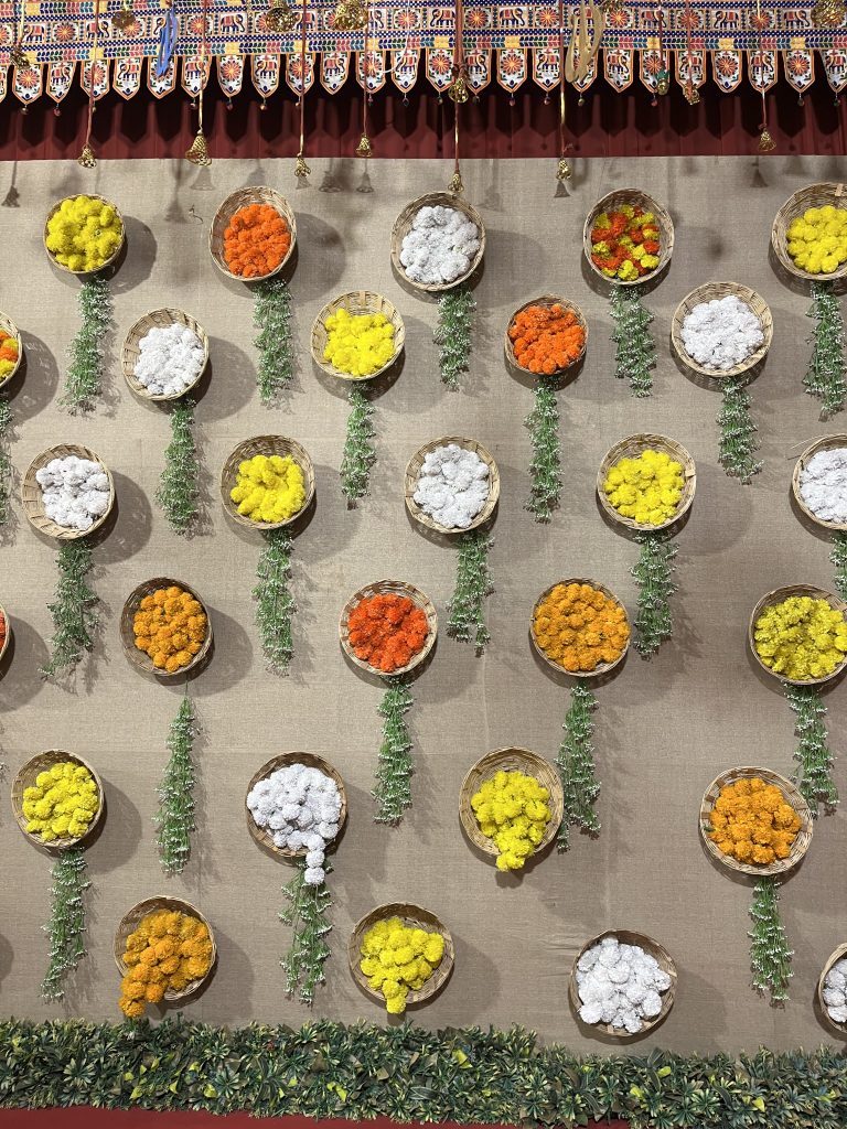 A decorative wall with circular baskets filled with vibrant artificial flowers in yellow, orange, white, and red.
