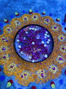 A bowl with floating pink rose petals and white flowers.
