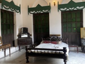A traditional bedroom featuring a wooden bed with a decorative headboard and white bedding adorned with two decorative pillows. 