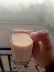 A human hand holding cup of tea. The background seems foggy winter morning.