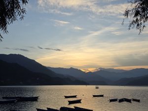 A serene lake at sunset, bordered by mountains in the background.