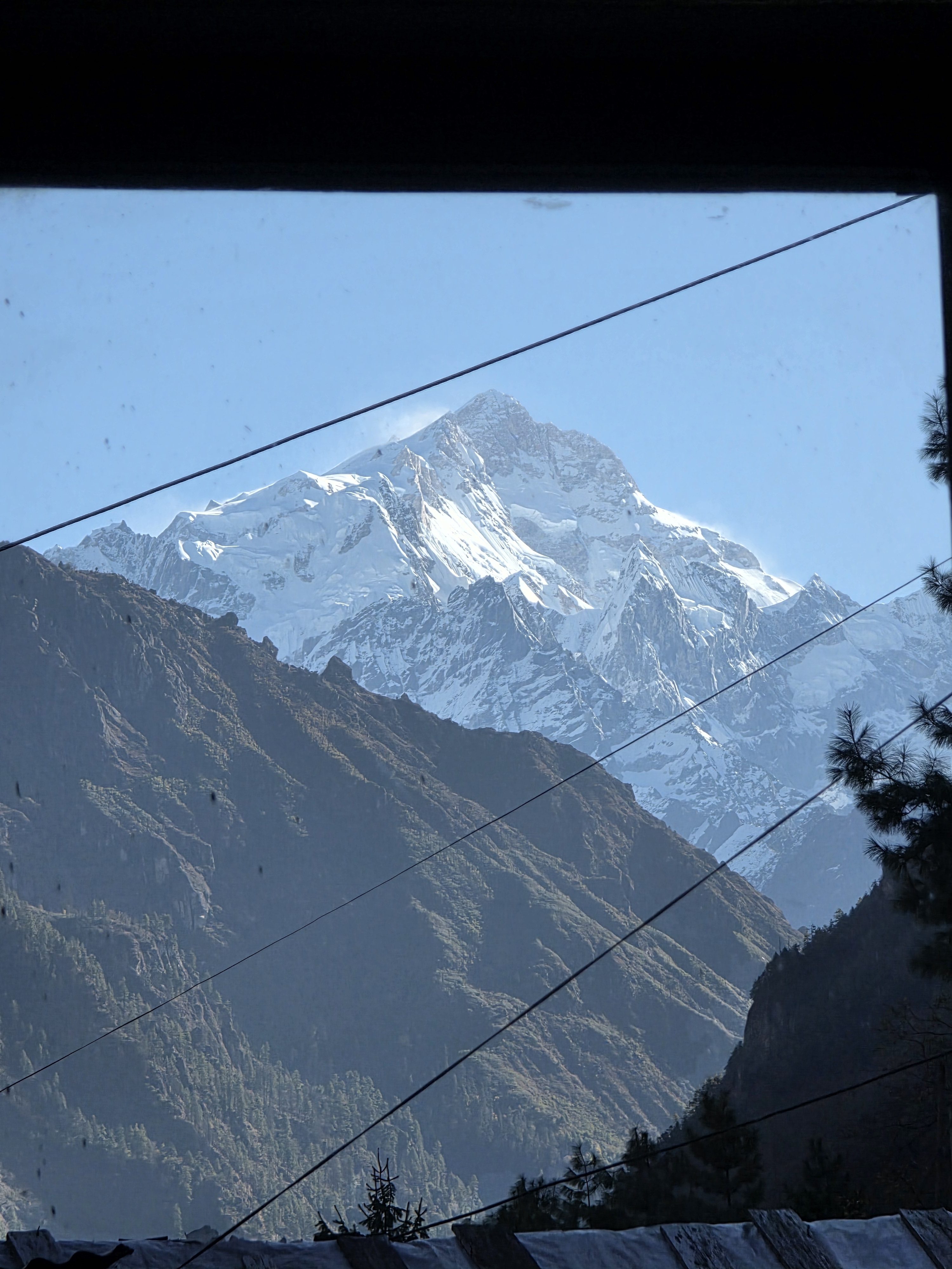 A panoramic view of a snow-capped mountain range, framed by a window.