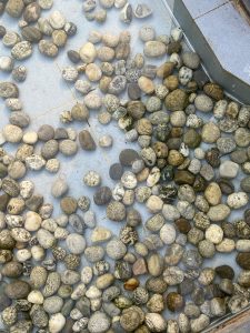 Multicolored pebbles scattered on a light blue tiled surface, varying in size for a textured look.