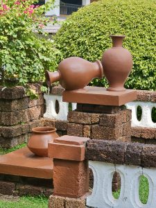 A water fountain set using clay plots and it is surrounded by a well maintained garden 