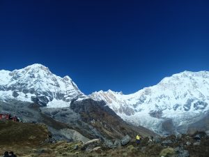 A panoramic view of snow-capped mountain peaks against a clear blue sky.