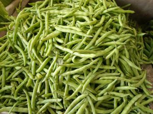 A close-up view of a large pile of fresh green beans, showcasing their elongated shapes and vibrant green color.