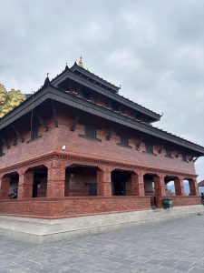 A red-brick, multi-tiered Sarangkot Temple with wooden carvings.