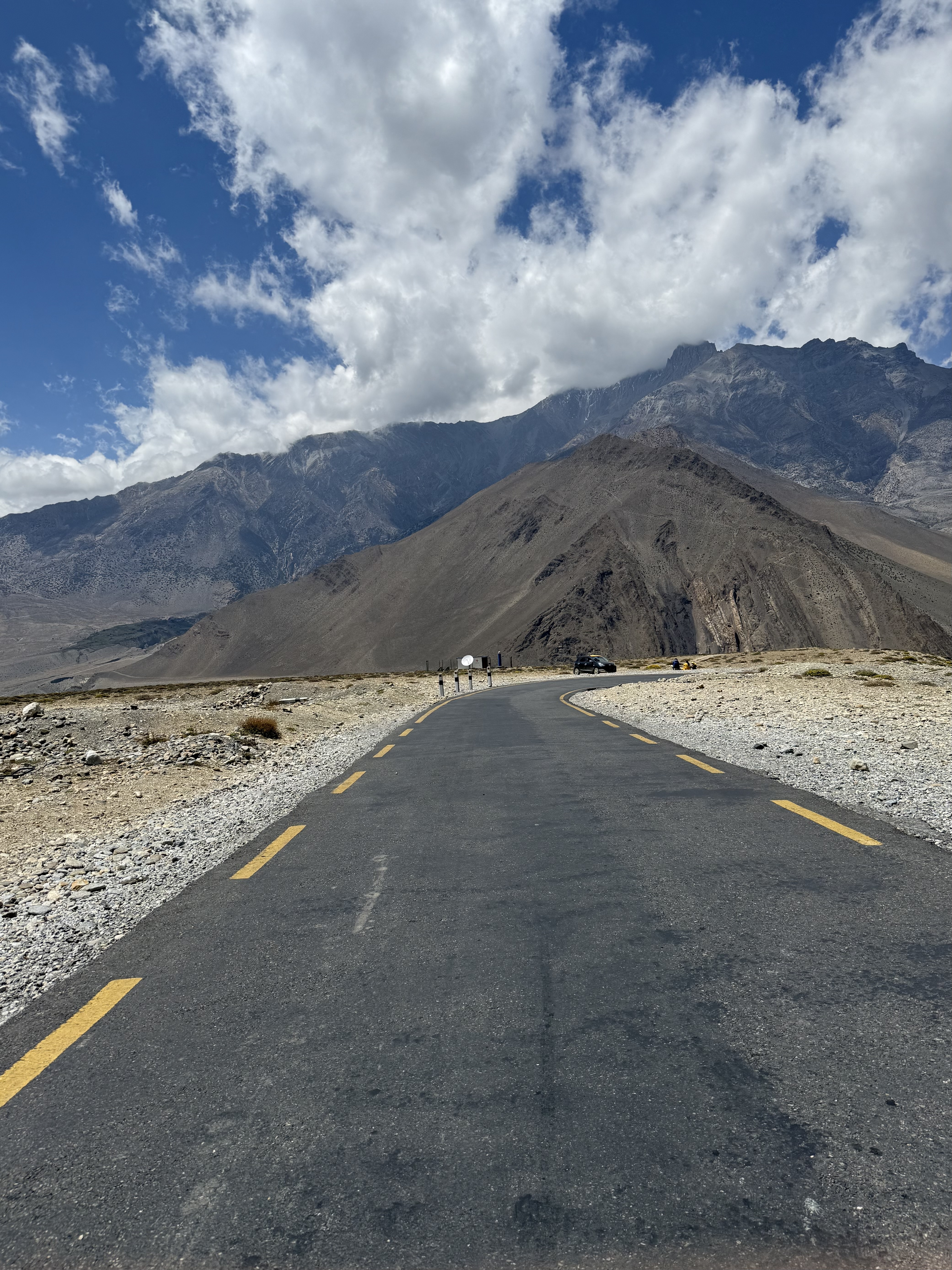 A paved road stretches into the distance, flanked by rocky terrain and mountains.