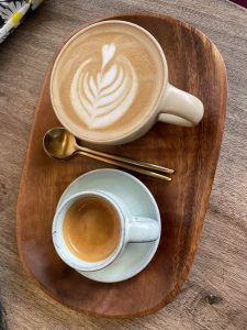 A top-down view of a wooden tray with two coffee cups. 