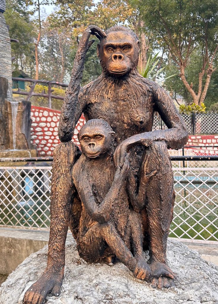 A bronze statue of two monkeys sits on a circular stone base.