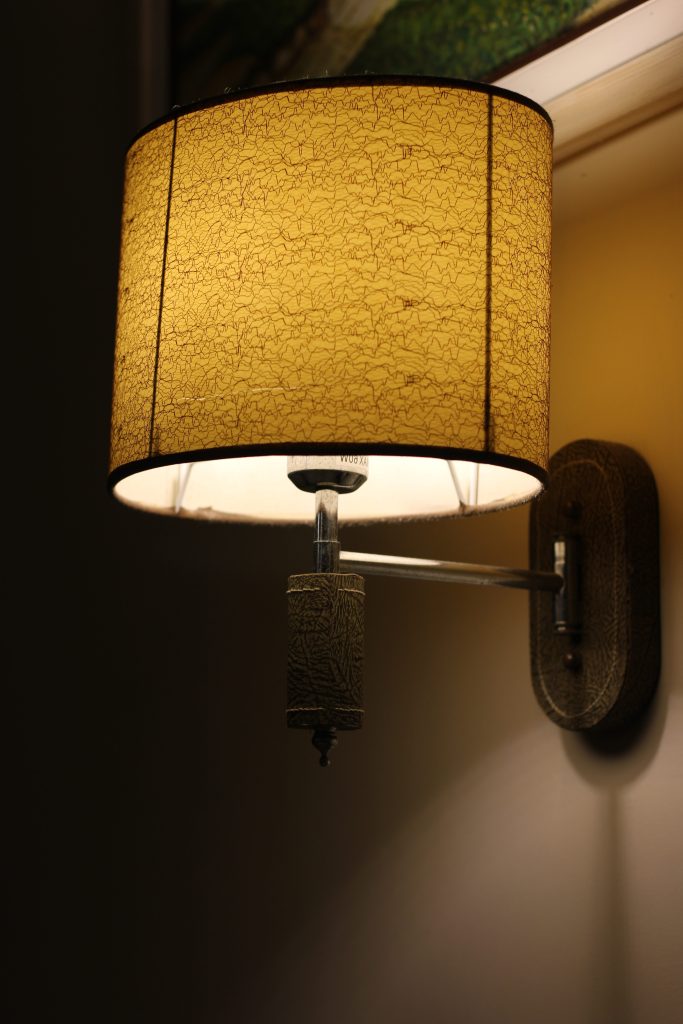 A wall-mounted lamp featuring a textured, warm yellow lampshade with a cracked pattern.