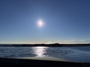 A peaceful Pacific sunrise viewed from Ichinomiya PA, with the sun reflecting on calm water and a distant shoreline.