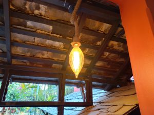 A warm, glowing pendant light hangs from a wooden ceiling with visible beams.