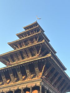A traditional multi-tiered temple with detailed wooden carvings at Bhaktapur Durbar Square.