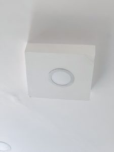 A square, white recessed ceiling light fixture mounted on a plain white ceiling.