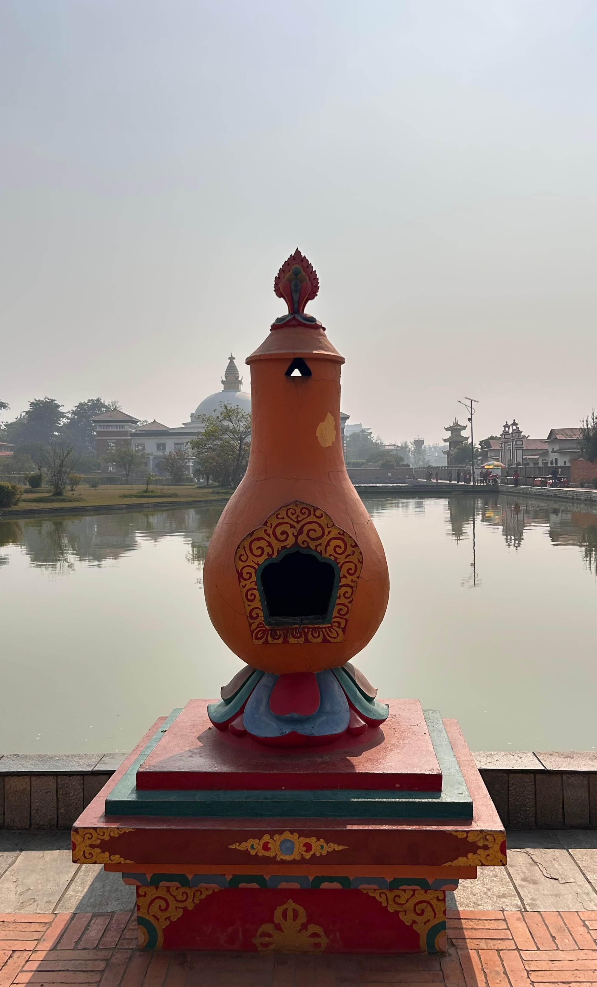 A colorful, ornamental structure resembling a large, traditional gourd sits prominently by the water’s edge.