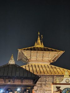 A nighttime view of a traditional temple complex featuring ornate rooftops and intricate woodwork. 