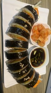 A plate of sliced gimbap, which is a Korean rice roll wrapped in seaweed.