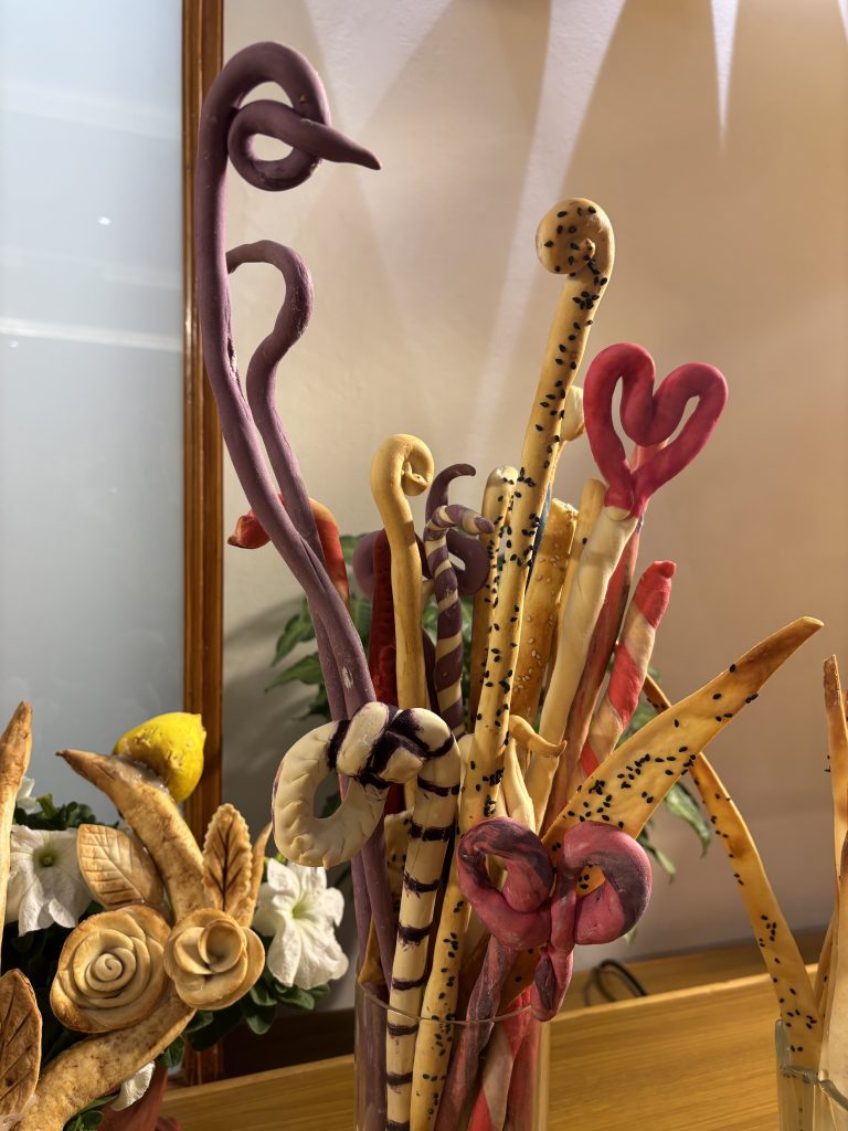 A collection of colorful, twisted artistic sticks displayed in a clear vase.