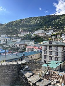 A panoramic view of a hillside village, featuring multiple buildings with a mix of traditional and modern architecture.