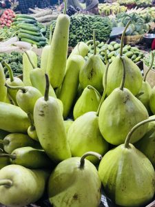 
A close-up view of a pile of green gourds, commonly found at a market. 