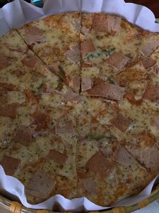 A freshly baked pizza displayed on a round plate, cut into triangular slices. 