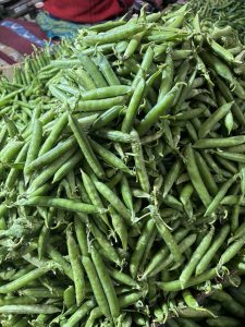 A close-up view of a large pile of fresh green peas, showcasing their vibrant color and smooth texture.