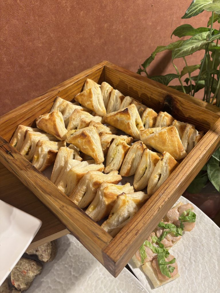 A wooden serving tray containing multiple golden-brown triangular pastries arranged neatly