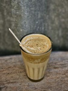 Cappuccino Style coffee served in a small tea glass with a thin wooden stir 
