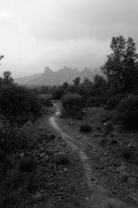 Black and white Sedona skyline view in the distance looking out along a muddy path. 