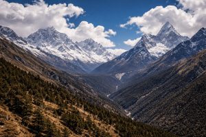A stunning Himalayan landscape with rugged mountains, lush valleys, and towering snow-capped peaks under a deep blue sky