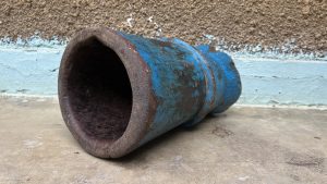A blue painted mortar placed on a veranda against a rough grey wall.