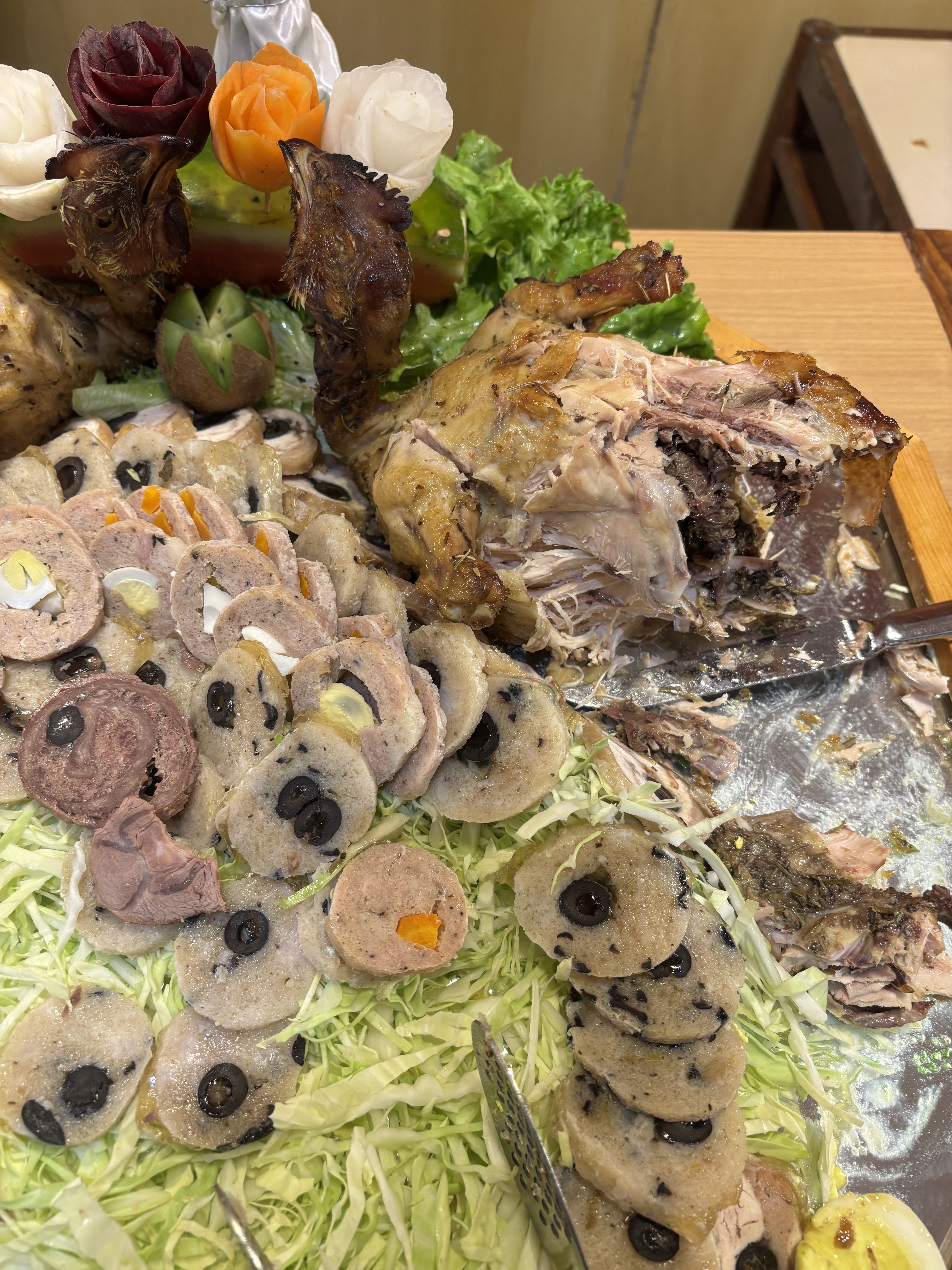 A close-up of a beautifully arranged platter featuring a roasted chicken, with a portion carved away to reveal the tender meat inside.