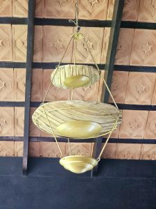 A beautiful display of traditional woven baskets and brass bowls hanging from the ceiling.