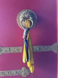 
A decorative door knocker shaped like a lion's head mounted on a vibrant red wall.