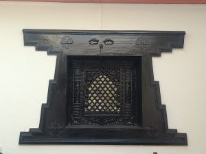 A decorative wooden window with intricate carvings surrounding its frame.