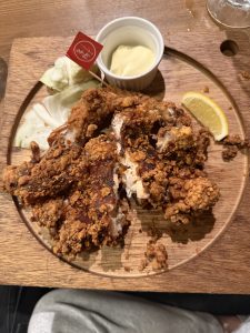Deep fried chicken served with a lemon wedge sauce and cabbage on a wooden board.