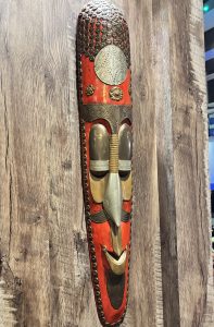 
A vibrant tribal mask mounted on a wooden wall