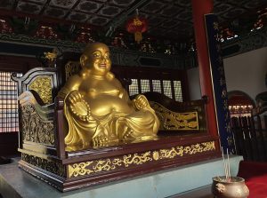 A large, golden statue of a seated figure, often associated with happiness and prosperity, adorned with a serene expression.