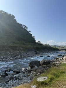 A serene landscape featuring a clear blue sky above a rocky riverbank.