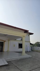 The image shows the exterior of a single-story building with a white facade and yellow decorative columns at the entrance.