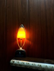 
A cozy bedside lamp emits a warm orange glow, sitting on a dark surface.