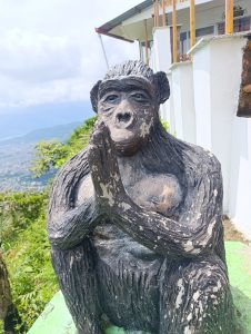 A statue of a monkey with a thoughtful expression, seated with its hands together in a praying or meditative pose.