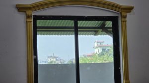 A large window with a black frame and decorative golden accents at the top.