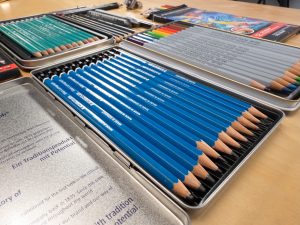 A photograph of drawing pencils that include graphite, ranging from H to B pencils, colored pencils, woodless pencils, matt pencils, and a pencil sharpener.