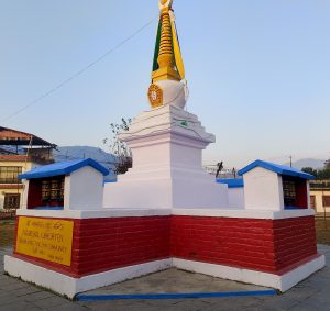 A decorative stupa, known as Namgyal Chhorten, is prominently displayed with a golden top and colorful banners. 