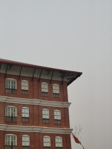 
A close-up view of a red brick building with a decorative cornice and multiple white-framed windows.