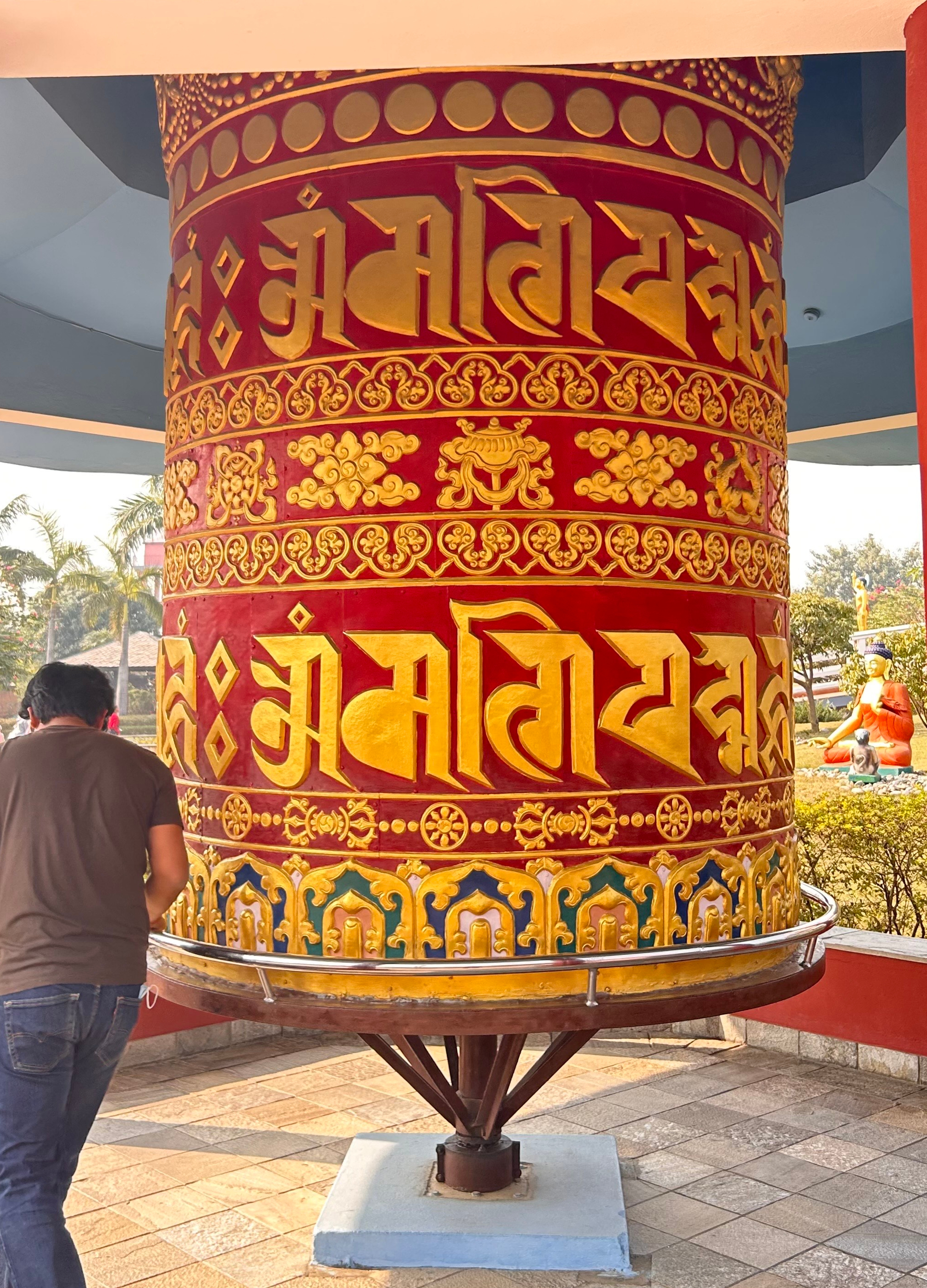 A large, colorful prayer wheel stands prominently, decorated in vibrant red and gold hues.